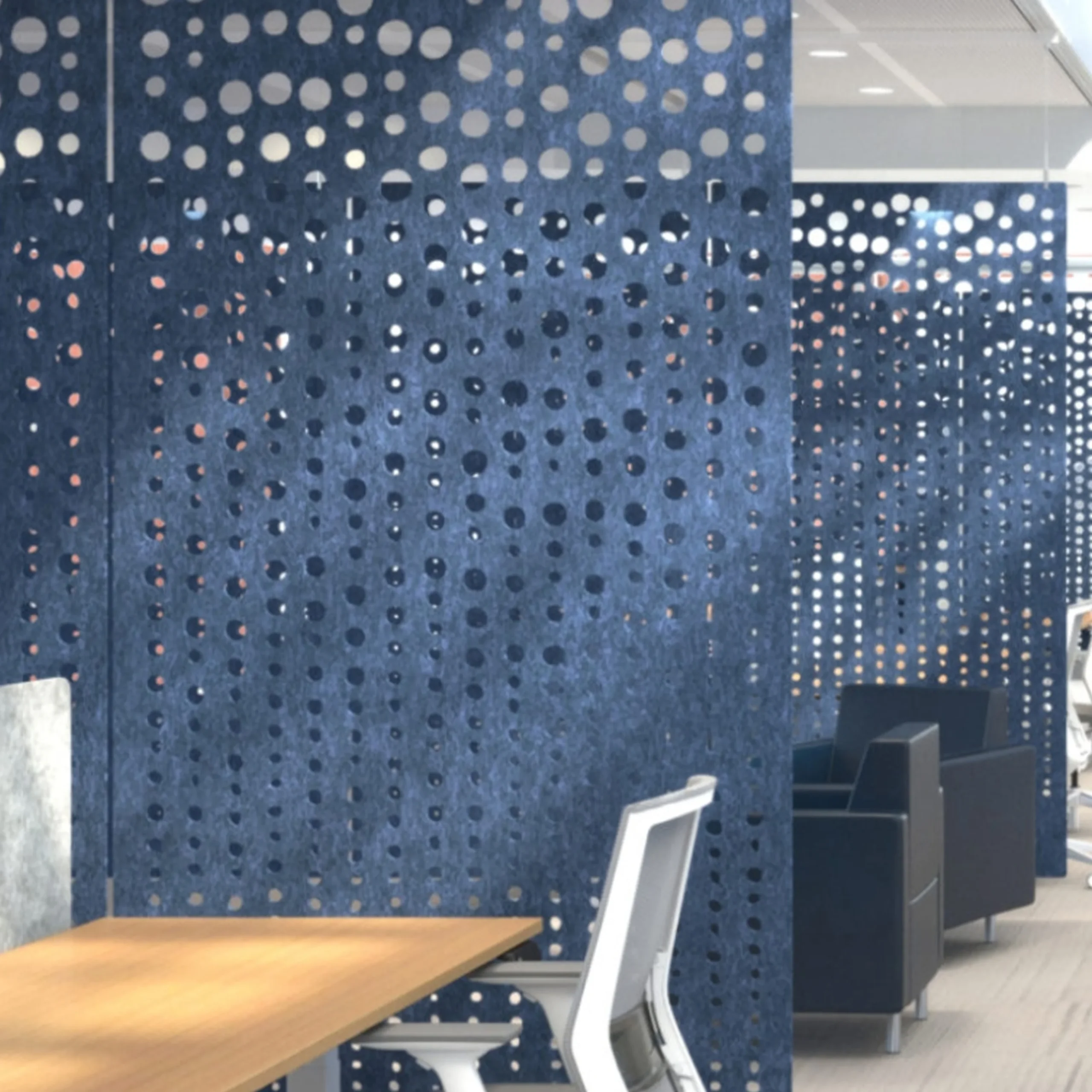 Open-plan office lounge with blue perforated panels, wooden tables, and white-framed seating.