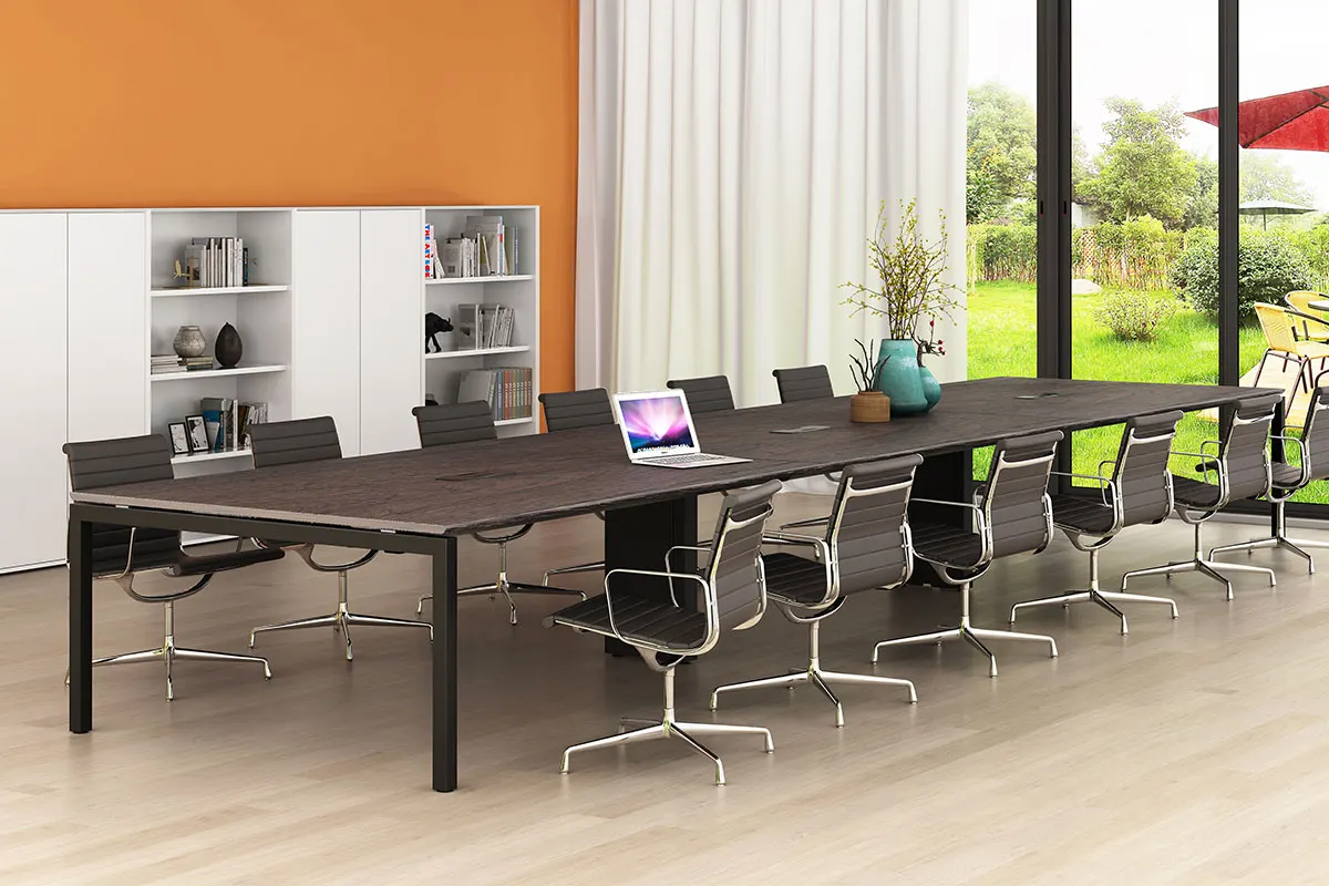 Modern conference room: long dark wood table with many black leather swivel chairs, white storage shelves against an orange wall, and large glass doors opening to a green outdoor area with patio furniture and a red umbrella.
