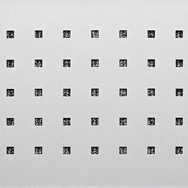 Close up of a light grey perforated panel with evenly spaced small black square holes in a grid pattern