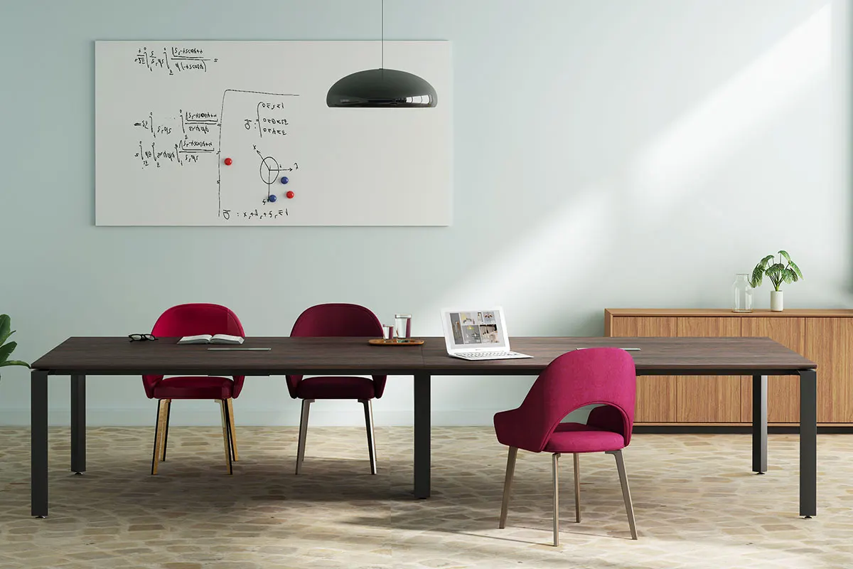 Modern conference room with a long dark table, magenta chairs, a hanging lamp, and a whiteboard with diagrams and equations on the wall.