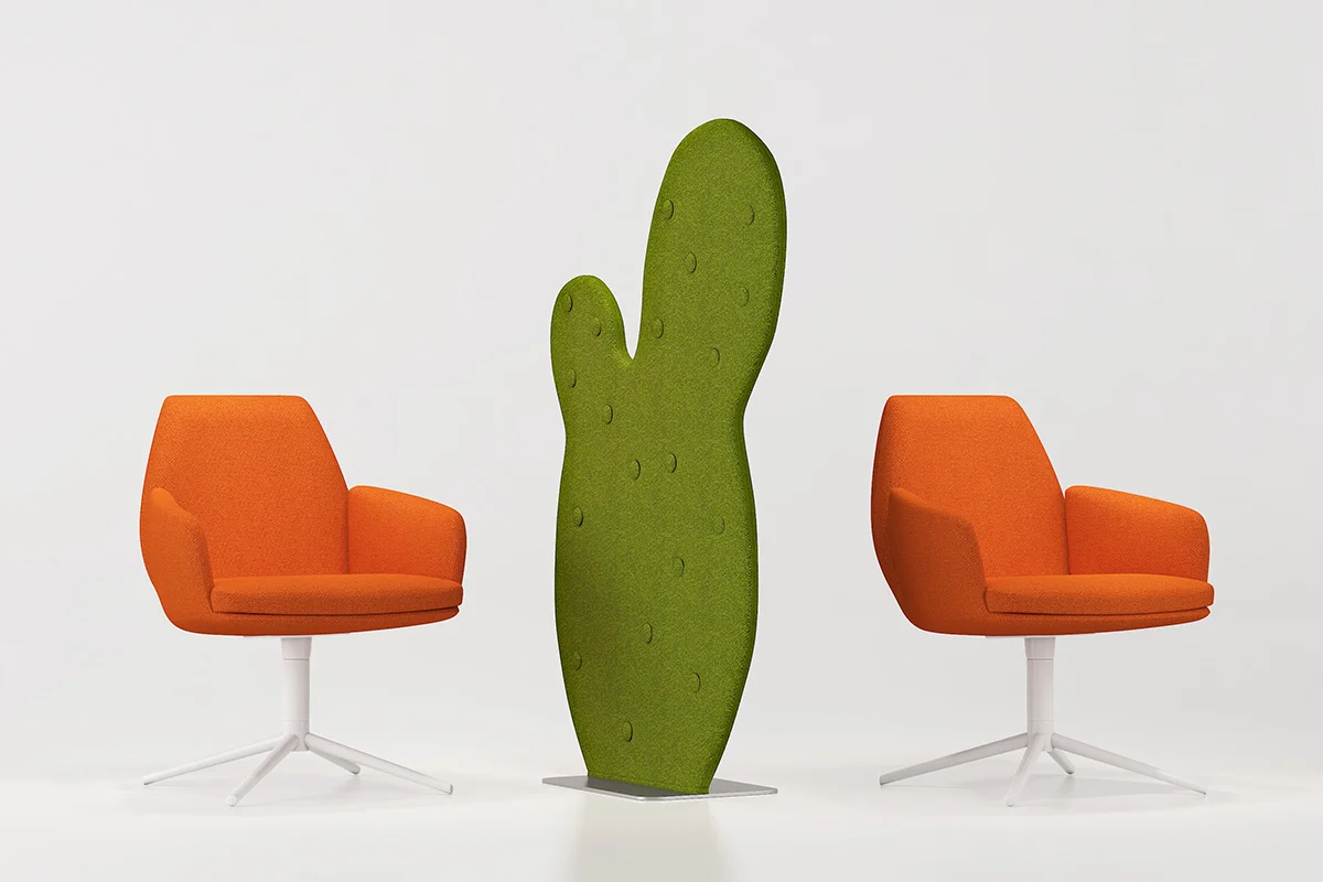 Two orange swivel chairs flank a tall green cactus-shaped room divider in a bright studio setting with white floor and backdrop steadied on a baseplate.