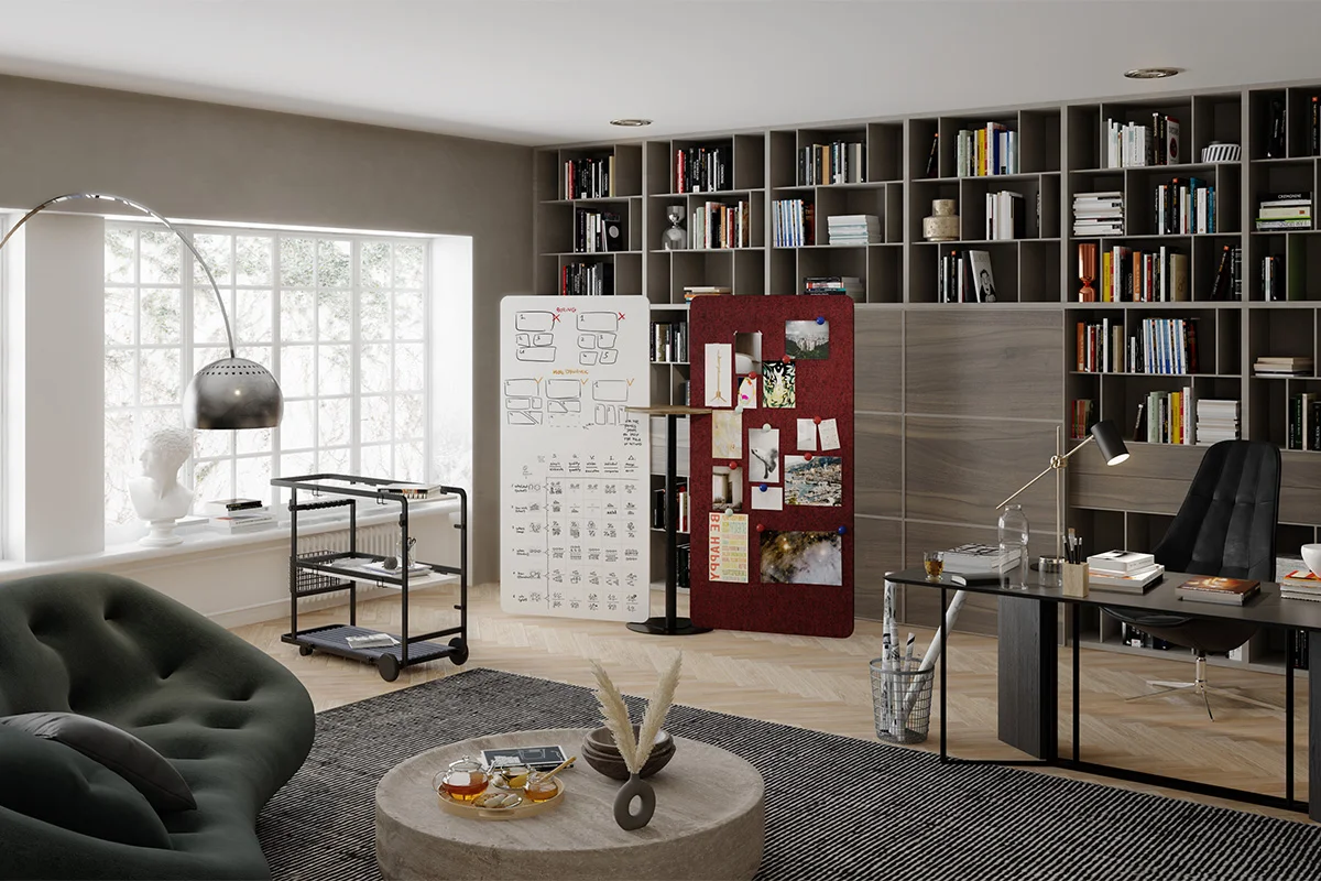 Modern home office with a dark desk, black chair, and floor-to-ceiling bookcases along a wall of shelves.