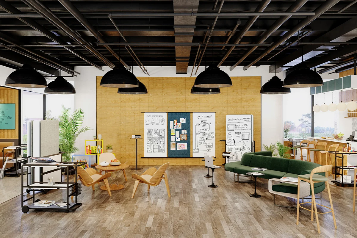 Open-plan coworking lounge with a green sofa, wooden chairs, plants, and whiteboards on a cork wall in the center workspace.