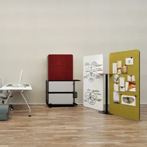 Open studio space with a whiteboard on wheels showing a diagram a red chair and a corkboard with notes on a wooden floor