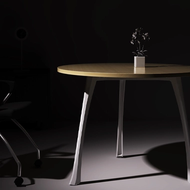 Round wooden table with slim metal legs in a dimly lit room, small plant on a white pot at center.