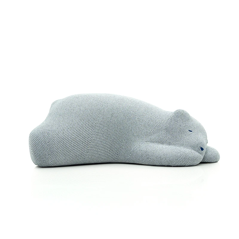 Light blue knitted plush cat shaped pillow resting on its side on a white surface