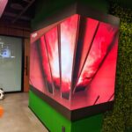 absen audio visual digital sign gp cabling solutoin center junho 2026 77 | gpcablingcombr Large red abstract display panel in a modern office space with green walls and a panda patterned cushion on an orange rug nearby