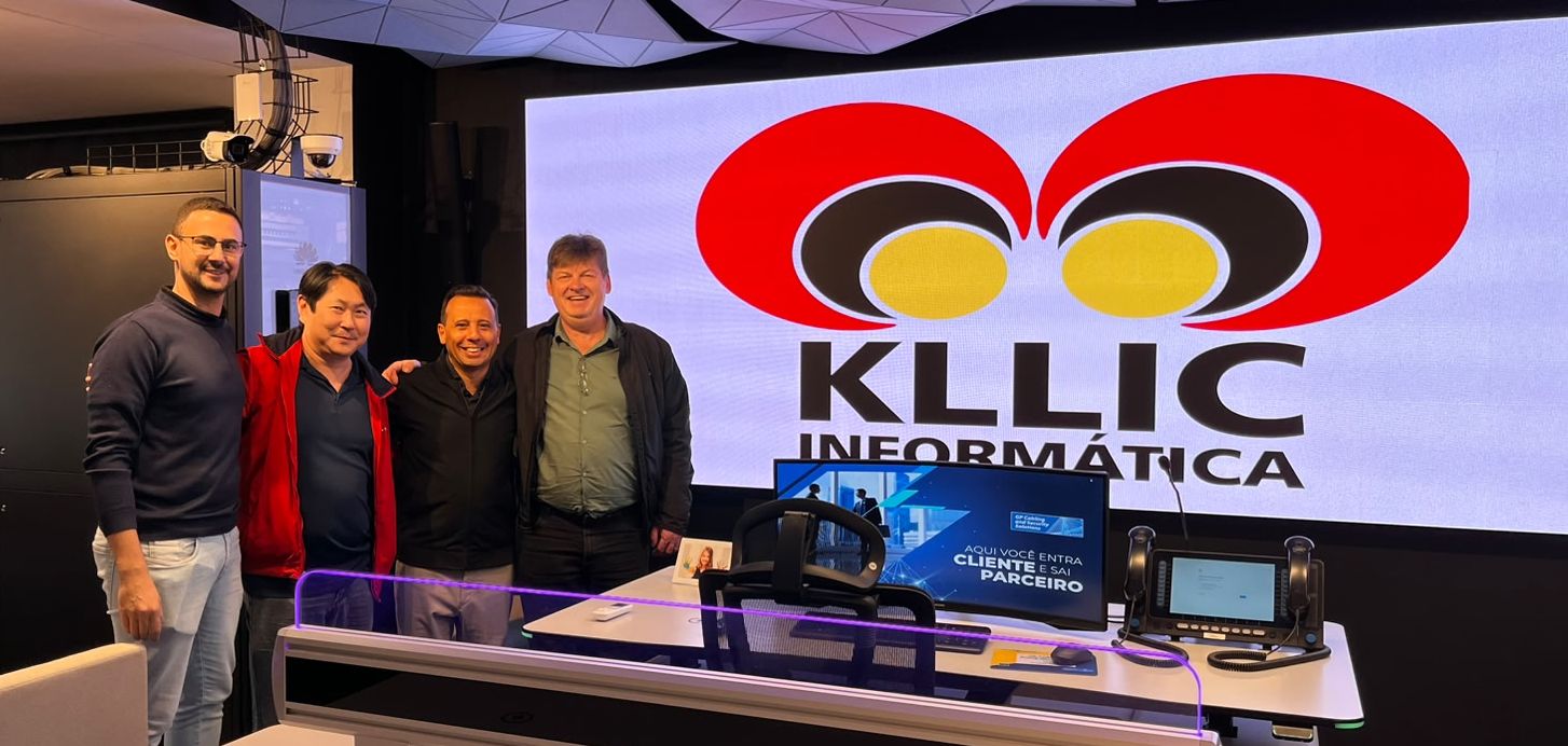 Four men stand together in a modern tech studio with a large screen showing the KLLIC INFORMATICA logo behind them.
