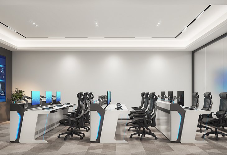 Modern computer lab with white desks, black ergonomic chairs, and multiple monitors in a bright, minimalist room with blue accents.