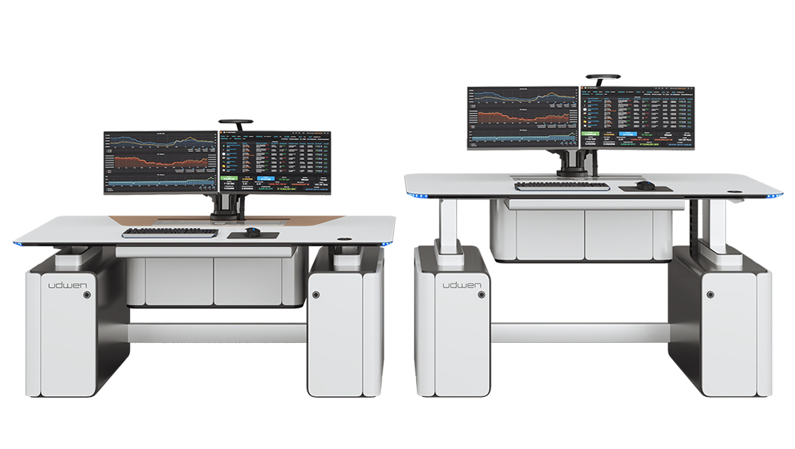 Two white trading desks with dual-monitor setups displaying stock charts and market data, with keyboards and mice on the desks.