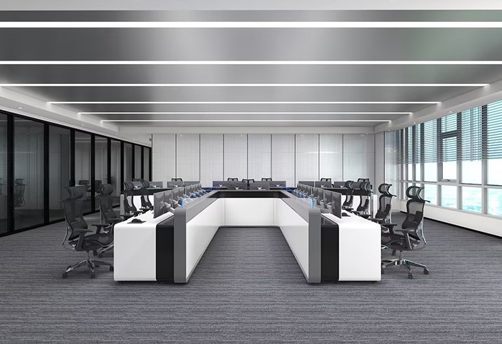 Modern conference room with a U-shaped white desk, black chairs, and large windows along the side.