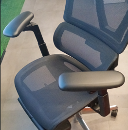 Blue ergonomic office chair with mesh back and padded armrests, seen from above.