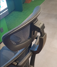 Close-up of an ergonomic office chair's curved mesh backrest and adjustable frame mechanism.