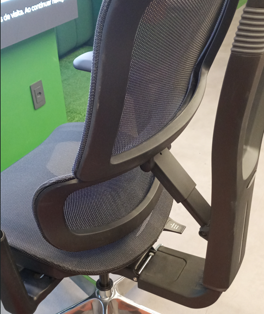 Ergonomic office chair with a mesh back and padded armrests, seen from the side in a workspace setting.