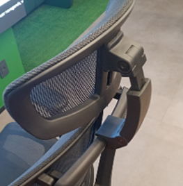 Close-up of a mesh-backed office chair showing the adjustable armrest and chair frame