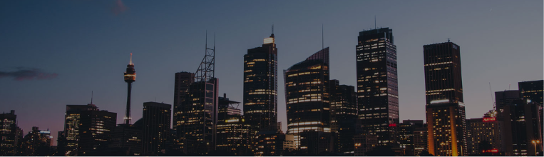 City skyline at dusk with illuminated windows and a dark blue sky