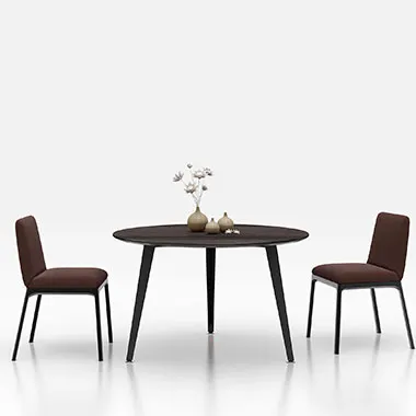 Round dark wood dining table with two brown upholstered chairs on a white studio backdrop; minimal vase centerpiece.