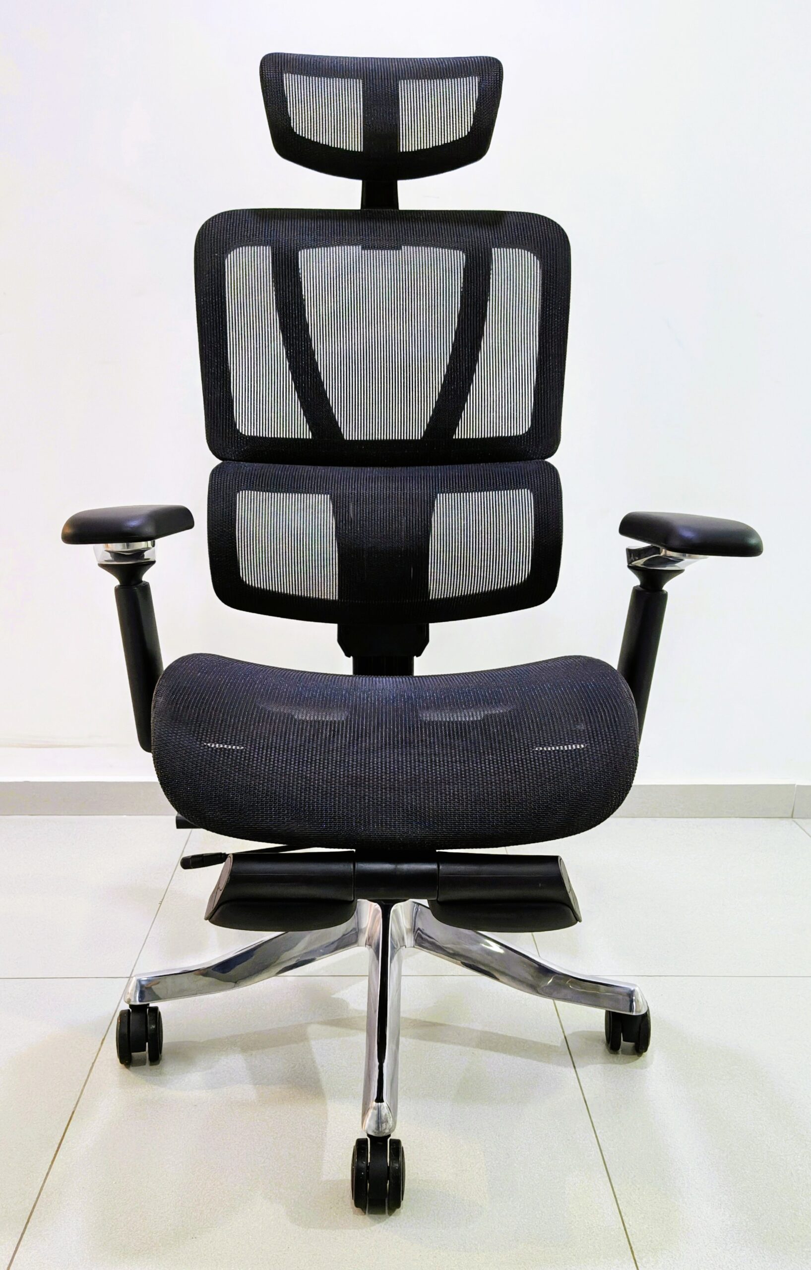 Ergonomic office chair with mesh back, headrest, padded armrests, and a chrome wheeled base.